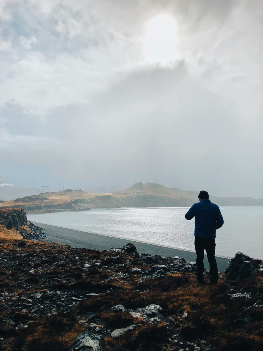 James looking across a bay from a rocky shore in Iceland.