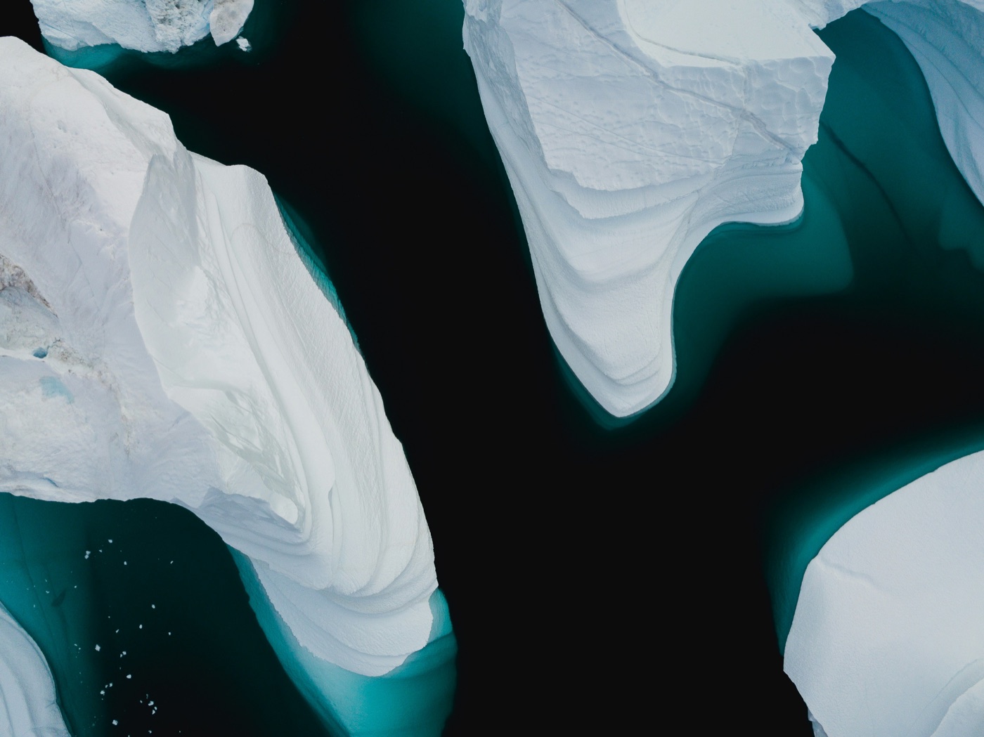 Icebergs seen from above, with turquoise edges beneath dark water.