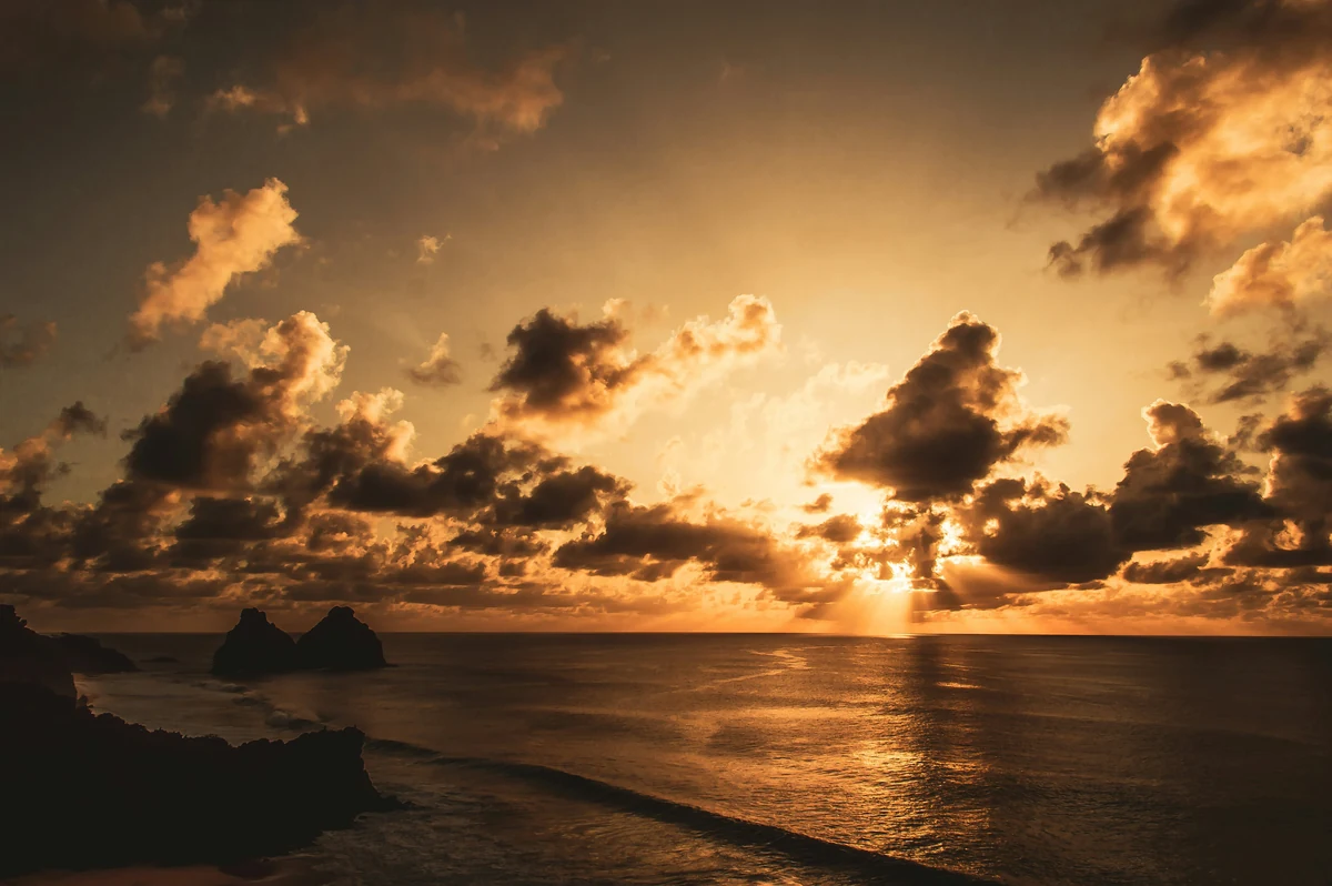 Warm sunlight breaking through clouds over the ocean.
