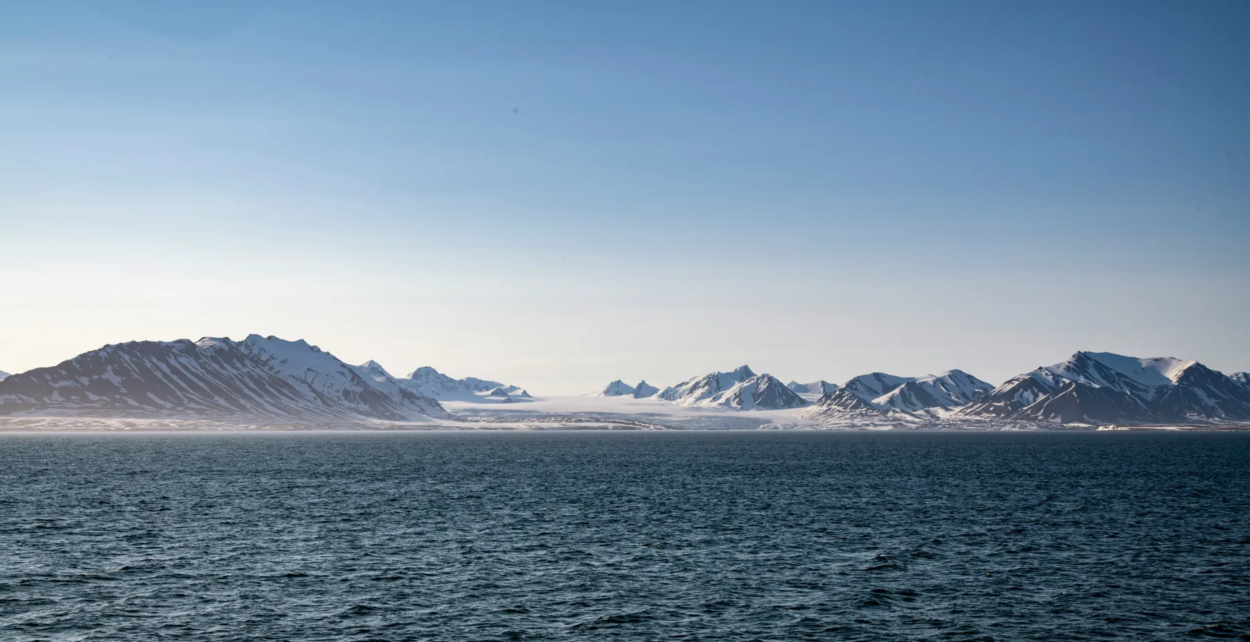 Snow-covered Arctic coastline across open water